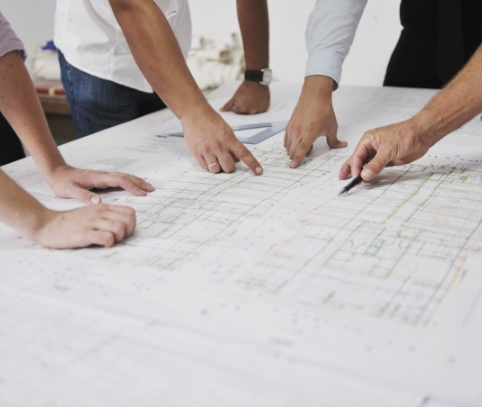 people pointing at chart on a table