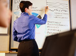 person writing on a dry erase white board